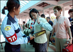 Passengers are screened with metal detectors at Thailand's Hat Yai airport after bombings that killed two.