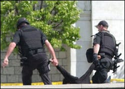 Captiol Police remove an unidentified man who stood in front of the U. S. Capitol Monday, April 11, 2005, with two suitcases.