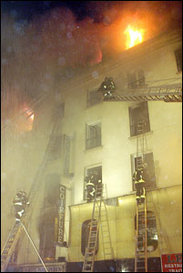 Paris firefighters attempt to save the lives of those trapped in a hotel that caught fire; at least 20 hotel residents are believed dead from the fire.