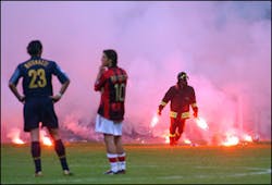 Inter Milan defender Marco Materazzi, left, and AC Milan Portuguese midfielder Rui Costa look on as a firefighter holds flares thrown by fans during their Champions League quarterfinal second leg match at the San Siro stadium in Milan, Italy. Stadium v