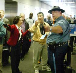 Massachusetts State Trooper James Doucette, right, directs people in a corridor at Boston's Logan International Airport Terminal B, Monday, April 25, 2005, as people return to the terminal following a partial evacuation. An unidentified woman was seen on