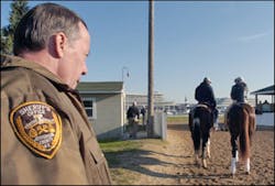 Jefferson County Deputy Sheriff Bill Luckhardt keeps a close watch on Kentucky Derby entrant Buzzards Bay, right, with Amy Mullins up, as trainer Jeff Mullins gets set to lead them on to the track Thursday, May 5, 2005, at Churchill Downs in Louisville