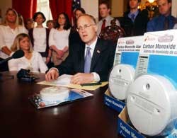 Gov. James Douglas, center, speaks at the Statehouse in Montpelier, Vt., Wednesday, May 11, 2005, as Ginger Aldrich, seated left, looks on.. Aldrich was critically injured when carbon monoxide leaked from a faulty boiler in the Redstone Apartments near th