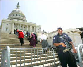 Capitol Police officer Donald Smith, right, holding a G36 assault rifle, stands guard as staff members and workers at the U.S. Capitol, return to the building following an evacuation, Wednesday, May 11, 2005, in Washington. The U.S. Capitol and White Hous