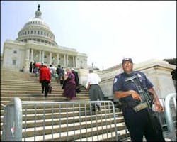 Capitol Police officer Donald Smith, right, holding a G36 assault rifle, stands guard as staff members and workers at the U.S. Capitol, return to the building following an evacuation, Wednesday, May 11, 2005, in Washington. The U.S. Capitol and White Hous