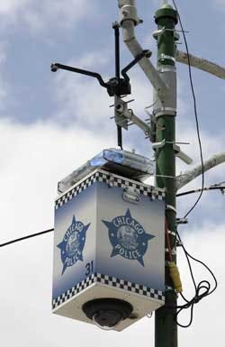 A Chicago Police Department surveillance camera is seen mounted on a light pole Tuesday, June 14, 2005, on the city&apos;s South Side. The black spider-like device mounted above the camera is a Smart Sensor Enabled Neural Threat Recogniton and Identification,