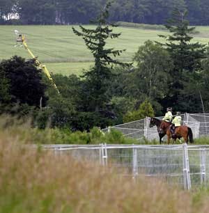 Police officials ride a secured perimeter around the G-8 Summit, being held at the Gleneagles Hotel in Scotland. What appears to be surveillance cameras, mounted on a yellow boom in the top left of the photo, add video confirmation at the perimeter.