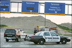 An airport police officer holds up police tape as a police vehicle arrives at the entrance to the Humphrey Terminal of the Minneapolis-St. Paul International Airport in Minneapolis which was evacuated, Wednesday, July 13, 2005, after security dogs detecte