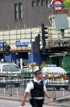 Police officers stand guard outside Stockwell Underground station in south London, Friday July 22, 2005, where a man who police believed to involved in terrorist incidents, was reported to have been shot.
