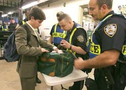 Jack Schinasi, of Yonkers, New York, left, has his bag inspected by members of the New York Police Department upon entering the Woodlawn subway station in the Bronx borough of New York, Friday July 22, 2005. Random inspections were made at the station whe