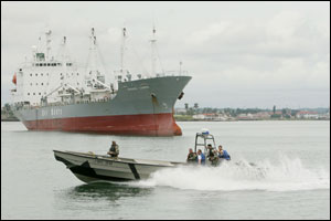 A Panama speedboat sails near a large anchorage cargo ship in Colon City, about 50 miles from Panama City, Panama Saturday, Aug. 6, 2005. Naval forces from 15 countries start the largest-ever multinational training exercise for the defense of the Panama C