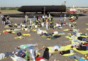 Volunteer 'victims' with simulated injuries lay on the ground waiting for aid following a simulated aircraft accident using a mock-up of a Boeing 737 aircraft, back ground, that runs off the runway and is engulfed in flames, as part of EPEX 2005, a full-s