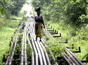 A woman walks along an oil pipeline near Shell's Utorogu flow station in Warri, Nigeria. Militia fighters have attacked an oil platform and kidnapped oil industry workers in the country.