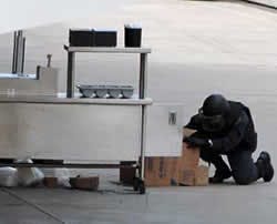 A member of the bomb squad investigates a hot dog cart with a suspicious package in it after fans and media were evacuated from Cox Arena at San Diego State University for a bomb scare before the scheduled start of the first round of the NCAA college bask A member of the bomb squad investigates a hot dog cart with a suspicious package in it after fans and media were evacuated from Cox Arena at San Diego State University for a bomb scare before the scheduled start of the first round of the NCAA college bask