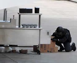 A member of the bomb squad investigates a hot dog cart with a suspicious package in it after fans and media were evacuated from Cox Arena at San Diego State University for a bomb scare before the scheduled start of the first round of the NCAA college bask