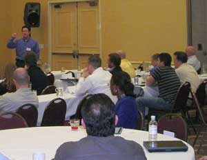 Kyle Candler (standing) kicks off a recent session at a touring roadshow from ScanSource which brought together VARs, end users and integrators for discussions of new technology and IP-integration trends.