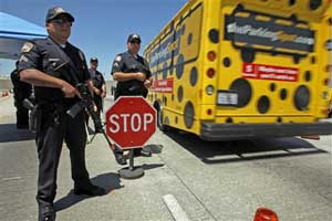 Los Angeles International Airport Police James Montano, left, holding a machine gun stands guard at a checkpoint at the entrance of the airport in Los Angeles Monday, July 2, 2007. Security measures were tightened in some U.S. airports since Saturday afte