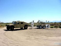 A Humvee tows a MP5000 vehicle barricade into position.