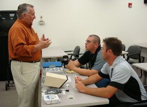 Bob Donovan (left), who reps ProTech, explains business opportunities of the ProTech technology to ADI Elk Grove Village inside sales reps Juan Garcia (seated, background) and Bill Behrens (seated, foreground) during the Outdoor Perimeter Protection Week.