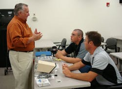 Bob Donovan (left), who reps ProTech, explains business opportunities of the ProTech technology to ADI Elk Grove Village inside sales reps Juan Garcia (seated, background) and Bill Behrens (seated, foreground) during the Outdoor Perimeter Protection Week.