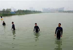 Frogmen wade out of the body of water after a security check near National Stadium, also known as Bird&apos;s Nest, background, in Beijing, Thursday, Aug. 7, 2008, a day before the opening ceremony of the Beijing 2008 Olympics.