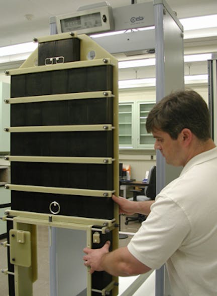 Guest researcher John Jendzurski prepares the NIST electromagnetic phantom for passage through the walk-through metal detector behind it. The carbon-polymer blocks of the phantom are arranged in a form that simulates the mass and height of the average A