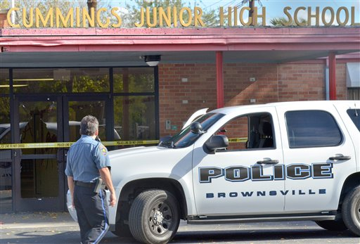 A Brownsville police officer looks at the shattered glass of the front door at Cummings Middle School after police shot and killed an armed eighth-grader who brandished a weapon in the main hallway.