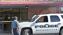A Brownsville police officer looks at the shattered glass of the front door at Cummings Middle School after police shot and killed an armed eighth-grader who brandished a weapon in the main hallway.
