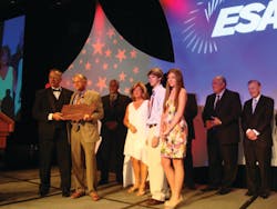 Dan Budinoff accepts the Morris F. Weinstock Person of the Year Award from Mike Miller, president of Moon Security Services Inc., Pasco, Wash., and last year&apos;s recipient at ESX 2012 at an awards ceremony. Also present are Budinoff&apos;s family members and past awards recipients.