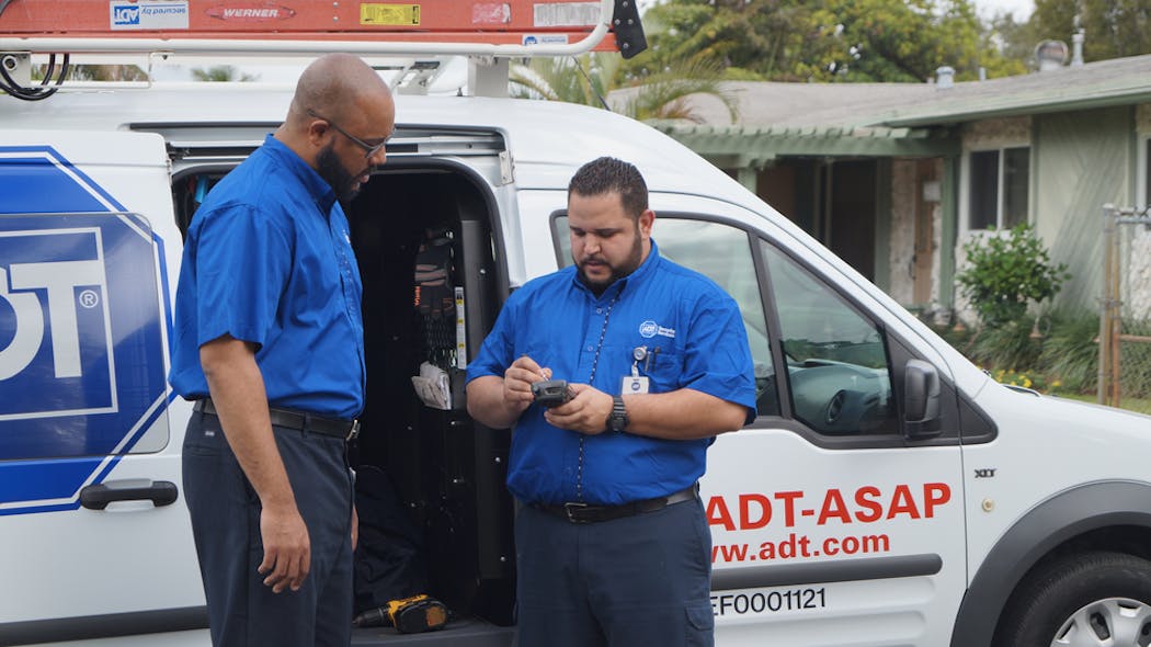 ADT Chief Marketing Officer Tony Wells gets ready for some installation work with Jesus, a service technician.