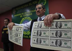 A police officer presents a sample of seized counterfeit U.S. dollars during a news conference in Lima, Peru, on Aug. 11. Police discovered nearly $2 million dollars in phony bills when they raided a restaurant that had a printing machine.