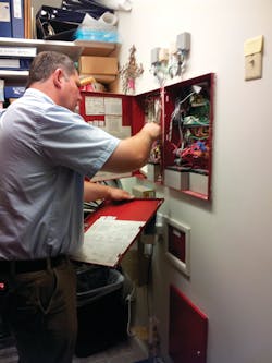 Service Manager Chip Wood, American Fire & Security/The Security Girl, performs a fire alarm system inspection as part of the company’s service contracts, of which some 85 percent of clients have opted into. Service Manager Chip Wood, American Fire & Security/The Security Girl, performs a fire alarm system inspection as part of the company’s service contracts, of which some 85 percent of clients have opted into.