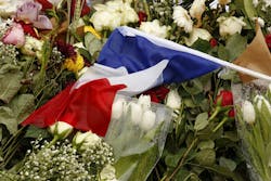 Light rain falls on memorial cards, flowers and candles in Paris on Thursday, Nov. 19, 2015.