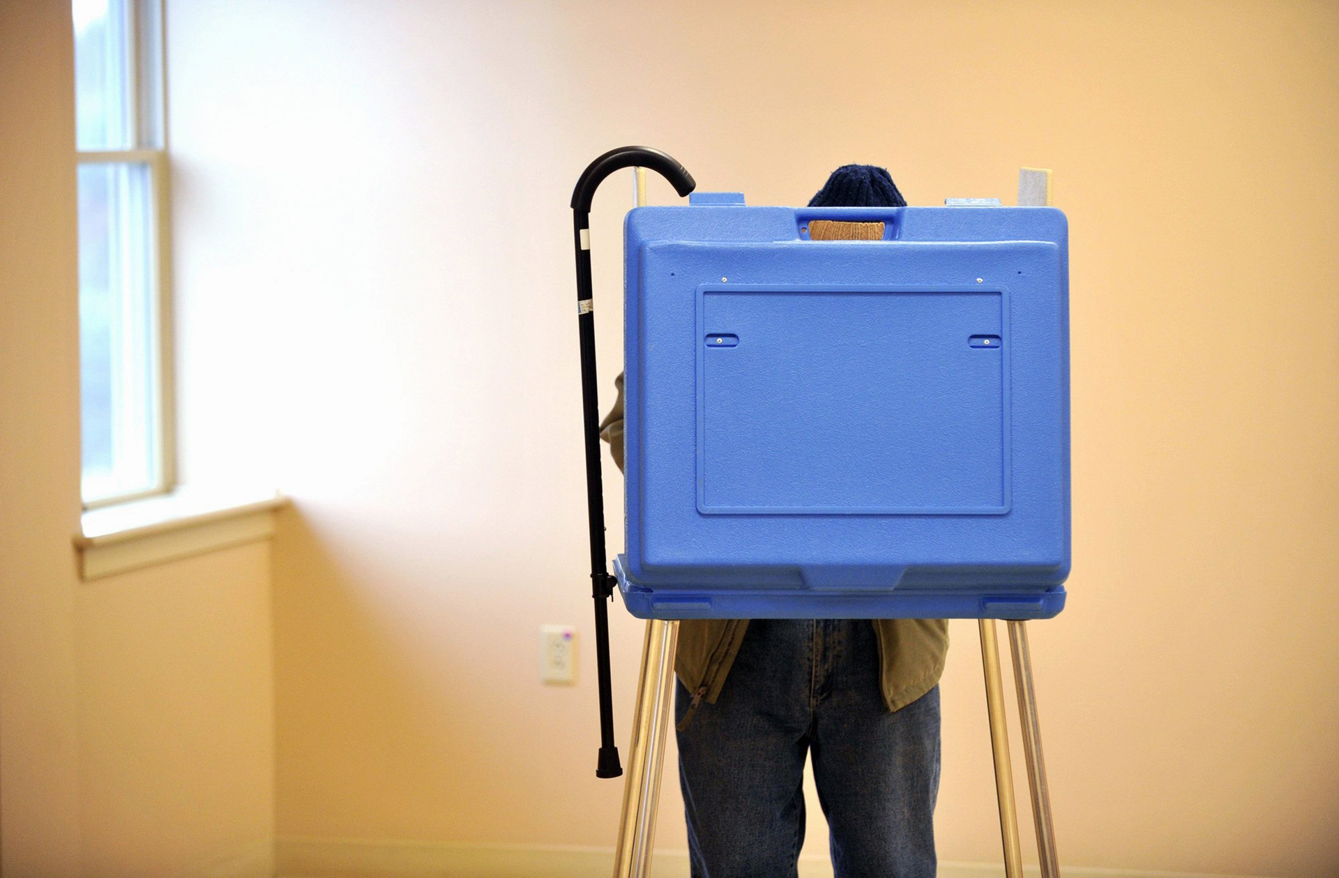 An elderly voter hangs his cane on the booth while voting in the State College Evangelical Free Church, in State College, Pennsylvania.