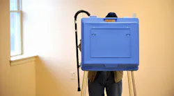An elderly voter hangs his cane on the booth while voting in the State College Evangelical Free Church, in State College, Pennsylvania.