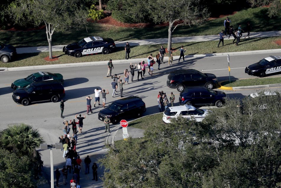 Students are evacuated by police out of Stoneman Douglas High School in Parkland, Fla., after a shooting on Wednesday, Feb. 14, 2018.