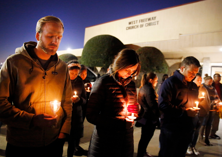 Church and community members, including Matt Pacholczyk, left, and his wife Faith Pacholczyk, gather outside the West Freeway Church of Christ in Fort Worth for a candlelight vigil, Monday evening, Dec. 30, 2019. A gunman shot and killed two parishioners before an armed security officer returned fire, killing him yesterday during their service.