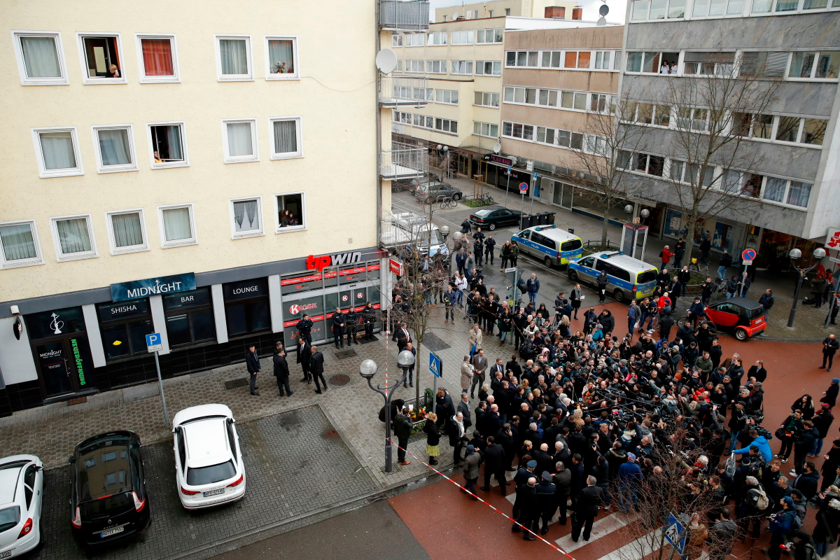 German Justice Minister Christine Lambrecht, German Interior Minister Horst Seehofer, Hesse's State Premier Volker Bouffier and Hesse state Interior Minister Peter Beuth speak to medias after laying flowers watched by people from their appartments above the 'Midnight' Bar, one of the bar targeted in a shooting at the Heumarkt in the centre of Hanau, near Frankfurt am Main, western Germany, on February 20, 2020, after at least nine people were killed in two shootings late on February 19, 2020. - The suspect in two shootings in Germany that killed at least nine people was found dead at home, police said on February 20, 2020. At least nine people were killed in two shootings late on February 19 in Hanau, near the German city of Frankfurt.