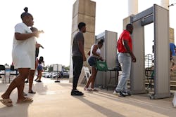 People walk through metal detectors to enter to Standridge Stadium on Aug. 19, 2022, in Carrollton, Texas.