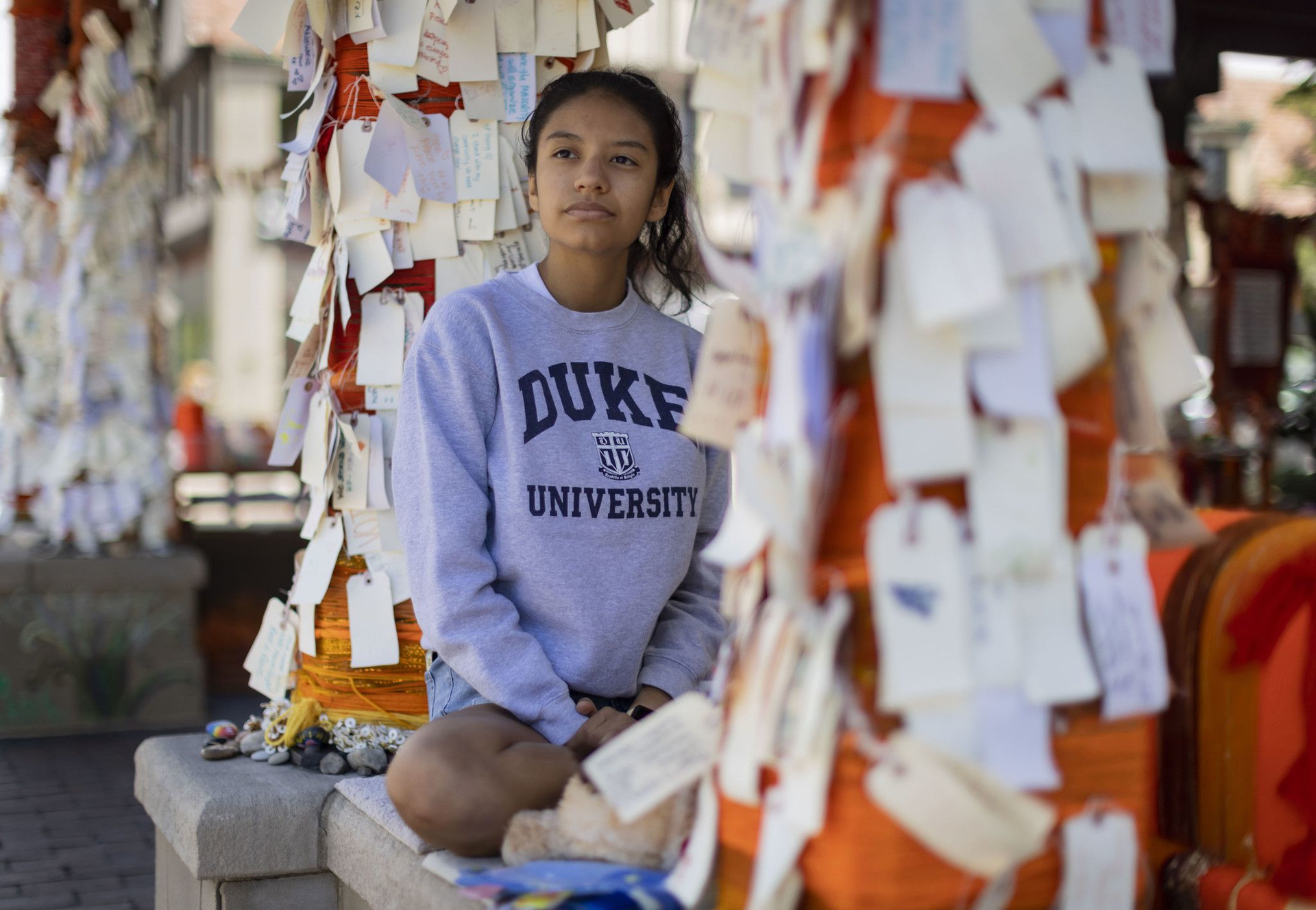 Stephanie Diaz, 16, a Highland Park High School junior, sits among messages left at the downtown memorial on Aug. 16, 2022, after the Fourth of July parade shooting.