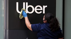 A worker cleans a sign in front of the Uber headquarters on May 18, 2020, in San Francisco, California.