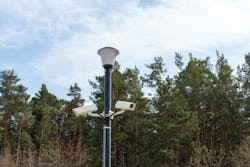 Surveillance cameras mounted on a lamppost at the side of a forest road. Surveillance cameras mounted on a lamppost at the side of a forest road.