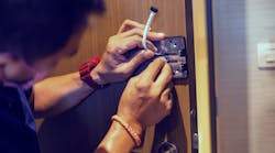 A service tech works on a digital door lock security system.