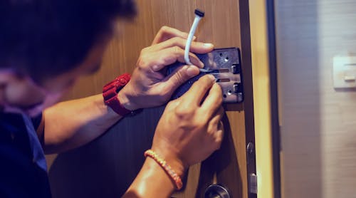 A service tech works on a digital door lock security system.