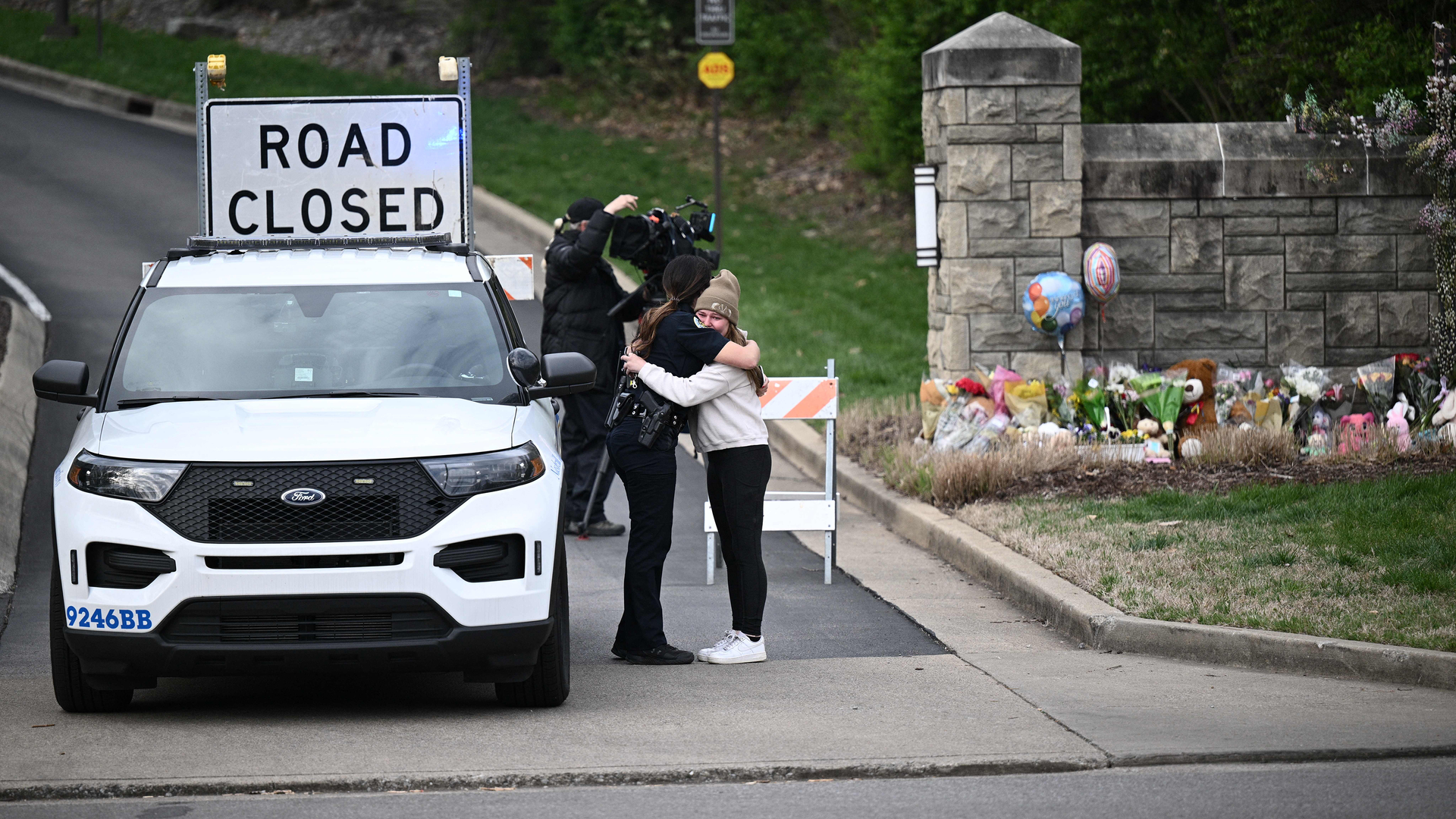 A woman hugs a police officer at the entrance of the Covenant School at the Covenant Presbyterian Church in Nashville, Tenn., March 28, 2023.