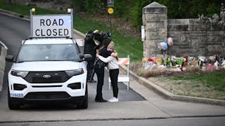 A woman hugs a police officer at the entrance of the Covenant School at the Covenant Presbyterian Church in Nashville, Tenn., March 28, 2023.