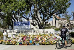 LAGUNA WOODS, CA - MAY 22: Warren Bidmead of Laguna Beach stops at the sidewalk memorial in front of the Geneva Presbyterian Church in Laguna Woods on Sunday, May 22, 2022. He said he rode past this location an hour before the shooting at the Irvine Taiwanese Presbyterian Church a week earlier. He said he couldn&apos;t imagine the horror of being together in church and this happening.