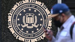 A pedestrian walks past a seal reading &apos;Department of Justice Federal Bureau of Investigation&apos;, displayed on the J. Edgar Hoover FBI building, in Washington, DC, on Aug. 15, 2022.