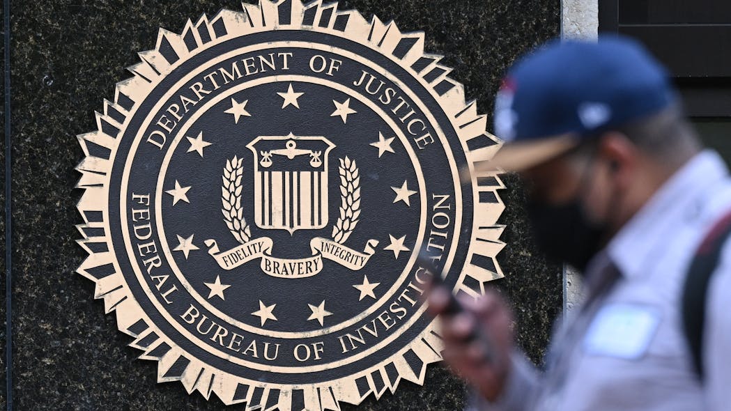 A pedestrian walks past a seal reading &apos;Department of Justice Federal Bureau of Investigation&apos;, displayed on the J. Edgar Hoover FBI building, in Washington, DC, on Aug. 15, 2022.