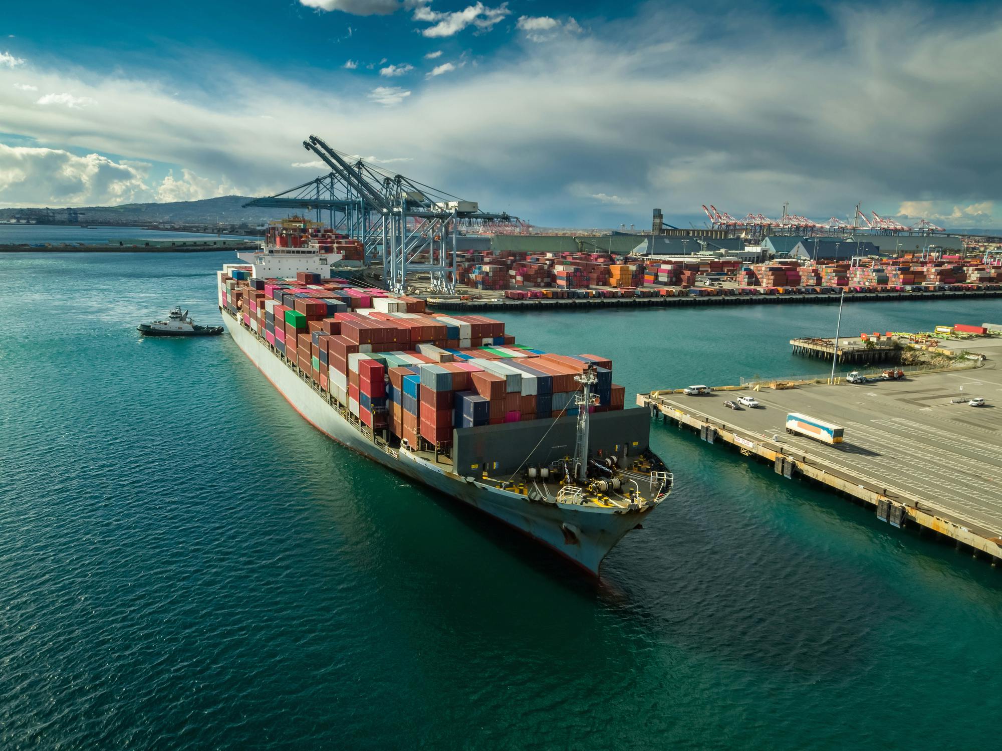 A tug boat maneuvers a cargo ship at dockside in Port of Long Beach, Calif..